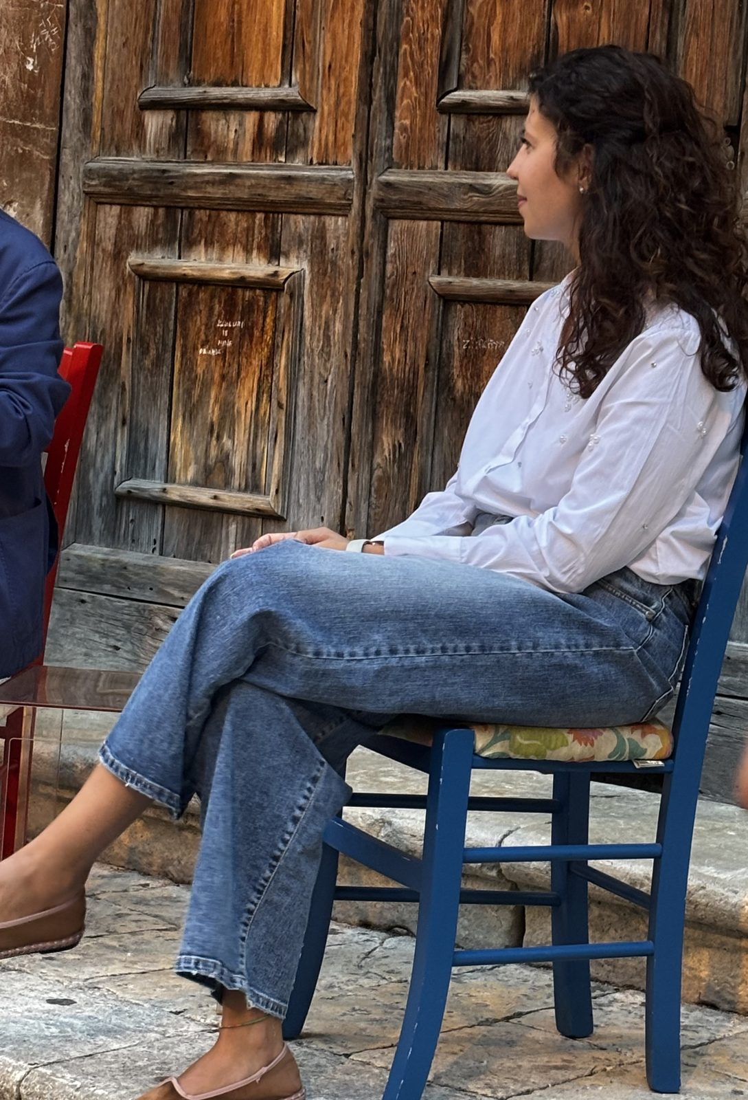 Miryam Cannizzaro seduta su una sedia blu davanti a un portone di legno